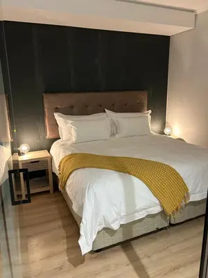 a bedroom with a large bed with a black wall at Thando's Luxury Stays at Ellipse, Waterfall in Midrand