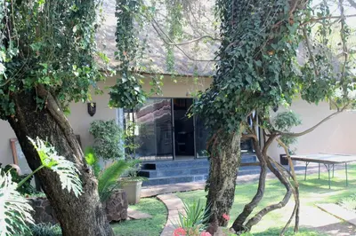 a house with trees and a table in the yard at ILANGA Lodge & Game Reserve in Kwarriekraal