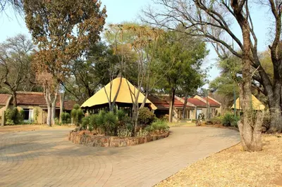 a gazebo in a park with a building at ILANGA Lodge & Game Reserve in Kwarriekraal