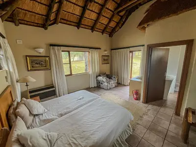 a bedroom with a large bed and a bathroom at ILANGA Lodge & Game Reserve in Kwarriekraal
