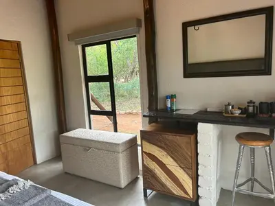a room with a fireplace and a mirror and a stool at Sabella Bushveld Lodge in Marble Hall