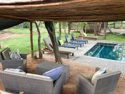 a group of chairs and a pool in a yard at Khanya Safari Lodge in Phalaborwa