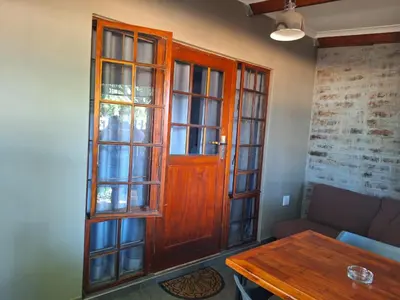 a living room with a wooden door and a table at 1@Kruger Unit 3 in Mokopane