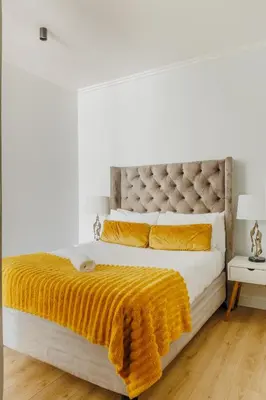 a bedroom with a large bed with an orange blanket at Elipse Waterfall-2802 in Midrand