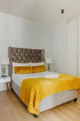 a bedroom with a large bed with a yellow blanket at Elipse Waterfall-2802 in Midrand