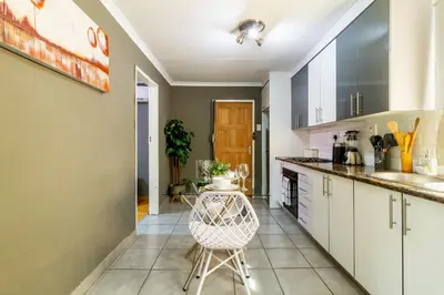 a kitchen with white cabinets and a chair in it at Cheerful Cottage in Johannesburg