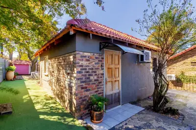 a small brick house with a door in a yard at Cheerful Cottage in Johannesburg