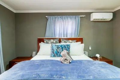 a bed with a blue blanket and pillows on it at Cheerful Cottage in Johannesburg