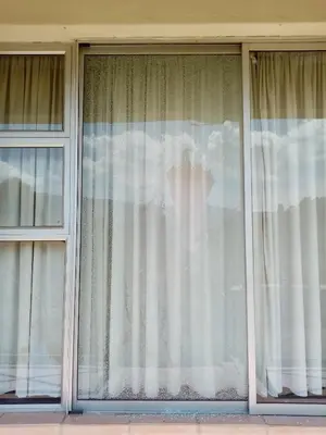 a window with white curtains on a building at Le Paradise holiday resort in Badplaas