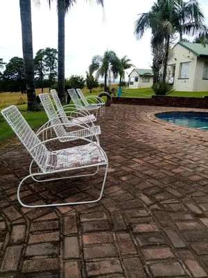 a group of white chairs sitting on a patio at Le Paradise holiday resort in Badplaas