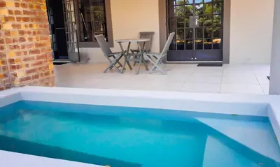 a pool with chairs and a table in a building at Tswenyane Kruger Riverview Apartments in Marloth Park