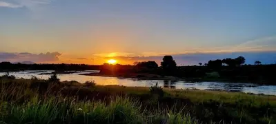 a sunset over a river with the sun setting at Tswenyane Kruger Riverview Apartments in Marloth Park