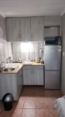 a small kitchen with a refrigerator and a sink at Tswenyane Kruger Riverview Apartments in Marloth Park