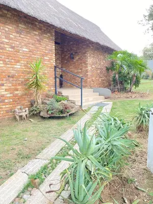 a brick building with a cat sitting on the stairs at Pop inn 74 in Midrand
