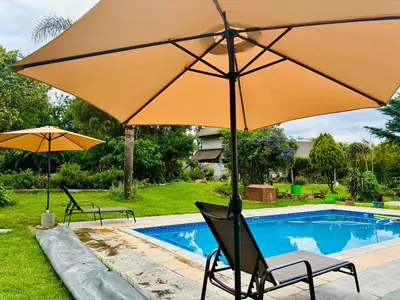 two chairs and an umbrella next to a pool at Pop inn 74 in Midrand