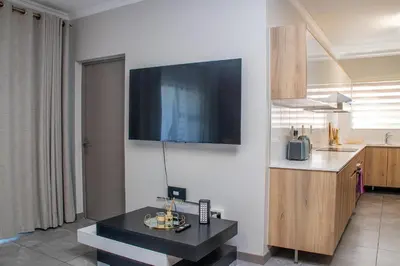 a living room with a tv on a white wall at Large 3 Bedroom Apartment in Midrand, Waterfall City - More space than a hotel room - Ideal for families, groups and work trips - 20 Elizabeth Place in Midrand