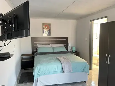 a bedroom with a bed and a flat screen tv at Exodus Guesthouse in Driekop