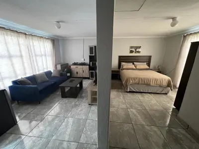 a bedroom with a bed and a blue couch at Exodus Guesthouse in Driekop