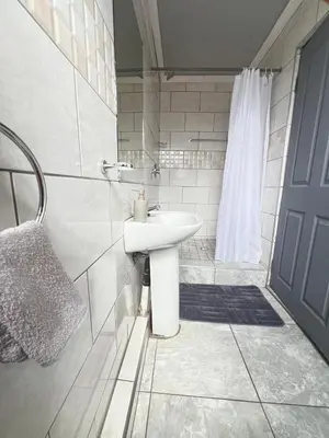 a white bathroom with a sink and a shower at Exodus Guesthouse in Driekop