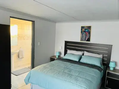 a bedroom with a large bed and a bathroom at Exodus Guesthouse in Driekop