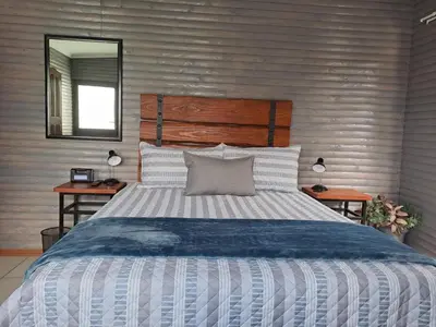 a bedroom with a bed with a wooden headboard and a mirror at Rustic Farm Stay in Lydenburg