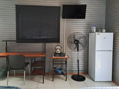 a kitchen with a table and a refrigerator and a fan at Rustic Farm Stay in Lydenburg