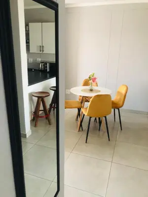 a dining room with a table and chairs and a mirror at Menlyn Place Vacay in Pretoria