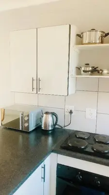 a kitchen with white cabinets and a tea kettle on the counter at Menlyn Place Vacay in Pretoria