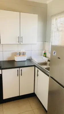 a kitchen with white cabinets and a refrigerator at Menlyn Place Vacay in Pretoria