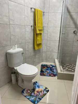 a bathroom with a toilet and a shower with yellow towels at The Garden Haven in Midrand