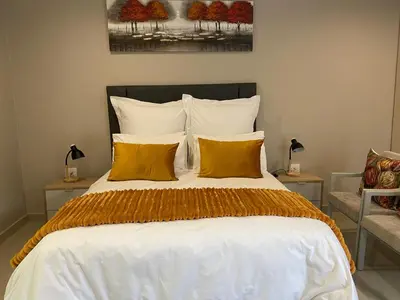 a bedroom with a large bed with yellow pillows at The Garden Haven in Midrand