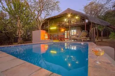 a house with a swimming pool in front of a house at Luxury GuesthouseCo HoneymoonHouse in Marloth Park