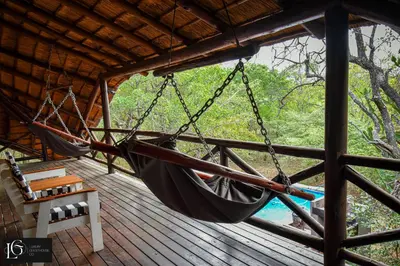 a hammock hanging from a roof on a porch at Luxury GuesthouseCo HoneymoonHouse in Marloth Park