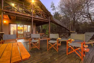 a wooden deck with chairs and tables and a house at Luxury GuesthouseCo HoneymoonHouse in Marloth Park