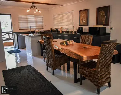 a kitchen with a wooden table and some chairs at Luxury GuesthouseCo HoneymoonHouse in Marloth Park