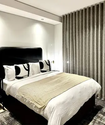 a bedroom with a large bed with black and white pillows at Explore Ellipse - Nguni Room in Midrand