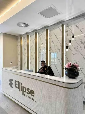 a man sitting at a reception desk in a lobby at Explore Ellipse - Nguni Room in Midrand