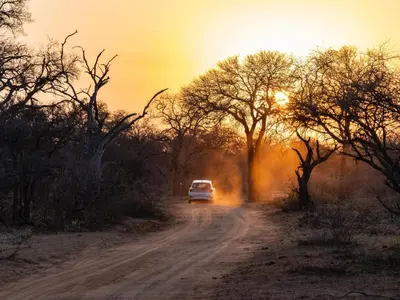 a car driving down a dirt road at sunset at Afrikaya Villas in Hoedspruit