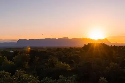 a sunset over a forest with mountains in the background at Afrikaya Villas in Hoedspruit