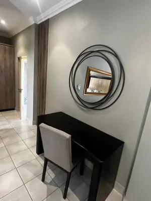a mirror on a wall above a desk with a chair at Sasavona Luxury Cottage - 631 Euphoria Golf & Lifestyle Estate in Naboomspruit