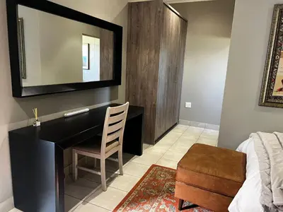 a bedroom with a desk with a chair and a mirror at Sasavona Luxury Cottage - 631 Euphoria Golf & Lifestyle Estate in Naboomspruit