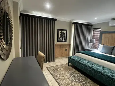 a bedroom with a bed and a table in a room at Sasavona Luxury Cottage - 631 Euphoria Golf & Lifestyle Estate in Naboomspruit