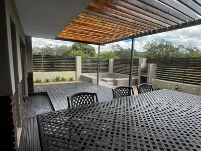 a patio with a table and chairs on a deck at Sasavona Luxury Cottage - 631 Euphoria Golf & Lifestyle Estate in Naboomspruit