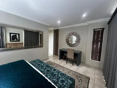 a bedroom with a bed and a desk and a mirror at Sasavona Luxury Cottage - 631 Euphoria Golf & Lifestyle Estate in Naboomspruit