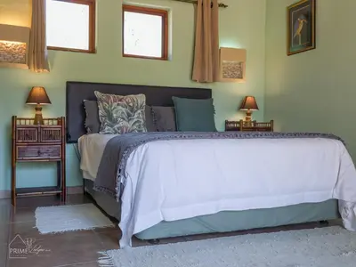 a bedroom with a large bed with two night stands at Hornbill House @ Zebula in Mabula