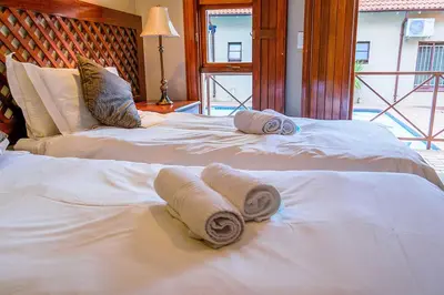 two beds with towels on them in a bedroom at RIETONDALE LODGE in Pretoria