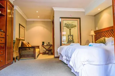 a bedroom with a large white bed and a couch at RIETONDALE LODGE in Pretoria