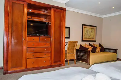 a bedroom with a large wooden cabinet with a flat screen tv at RIETONDALE LODGE in Pretoria