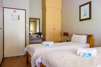 a hotel room with two beds with towels on them at RIETONDALE LODGE in Pretoria