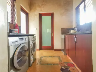 a laundry room with a washing machine and a kitchen at Nyala's Corner @ Zebula in Mabula